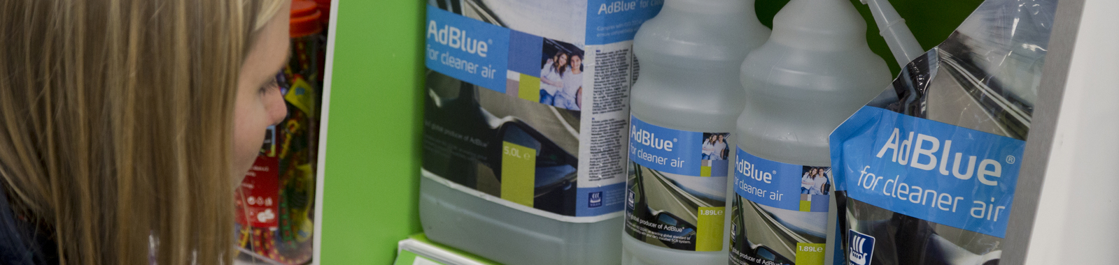 woman taking an AdBlue refill from a shop shelf